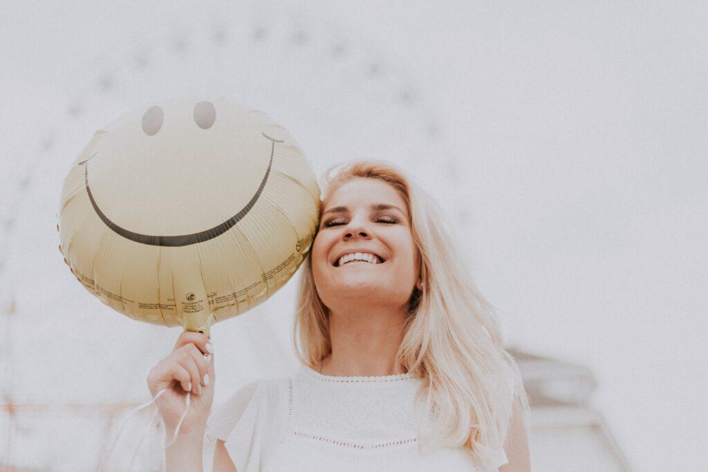 Macht-des-Lächelns-Tag, lächelnde Frau mit Smilie-Ballon